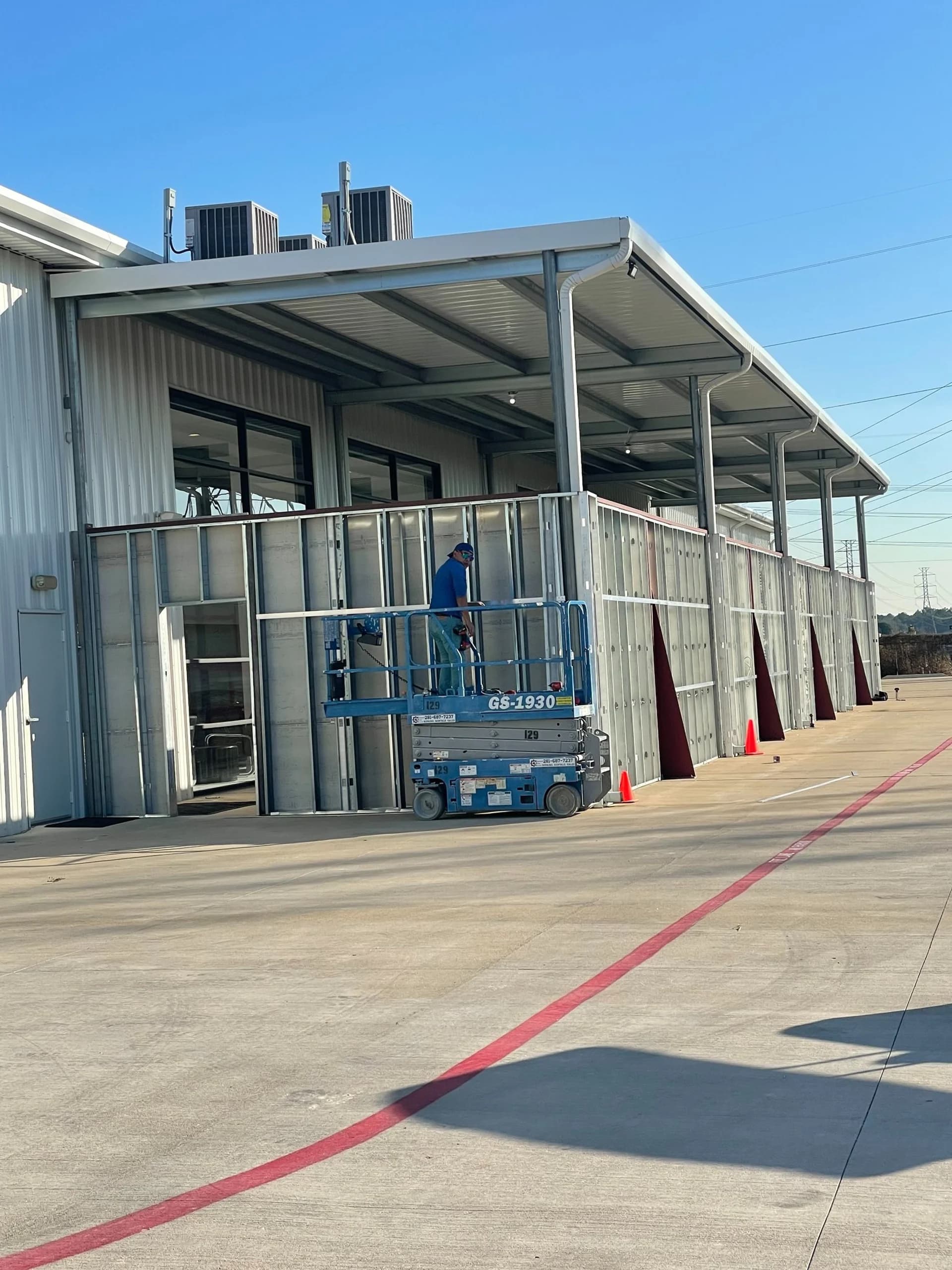 Crew installing a commercial metal canopy from a scissor lift